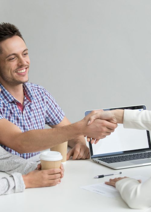 Happy couple greeting financial consultant Happy millennial couple smiling, greeting advisor or consultant making good first impression. Husband handshaking real estate agent after successful contract signing, closing deal, making agreement